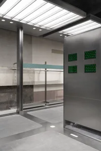 Seamless transition between metal and glass panels in a modern commercial space with concrete floor and ceiling.