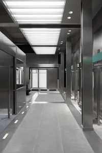 A modern, industrial-style office corridor with concrete floors and metallic columns.