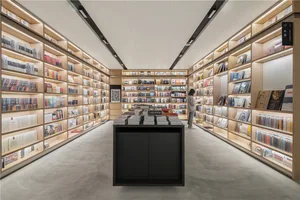 A minimalist library with wooden bookshelves filled with books and a central black island.