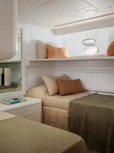 Minimalist bedroom with fabric and wood bedding, pillows, and a window.