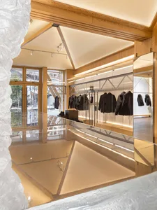 A modern minimalist clothing retail store featuring glass walls and wooden panels.