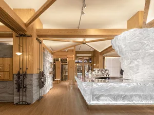 Modern coffee shop with wooden interior design, featuring a large ice sculpture and a coffee bar.