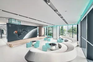 A modern office lounge featuring white and turquoise seating with concrete flooring and concrete seating areas, illuminated b
