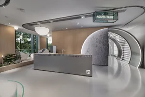 A modern, minimalist office space featuring metallic finishes, glass walls, and wooden accents, with a large circular metalli