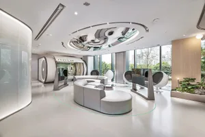 A modern office space featuring glass walls, concrete flooring, and contemporary furniture.