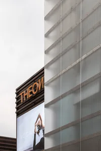 A modern commercial building with a glass façade and a sign that reads 'THEON YOGA PILATES'.