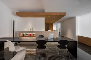 A modern office space featuring black tables and a wooden counter against a white and cork wall.