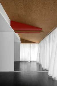 Modern minimalist bedroom featuring cork flooring and white curtains.
