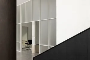 A minimalist commercial interior featuring a staircase with black tiled steps, a white frosted glass curtain wall, and a mode