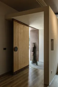 A modern interior with a wooden sliding door and a blurred figure walking through a corridor.