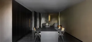 Modern minimalist kitchen with concrete countertops and floor, featuring sleek black cabinets and a central dining table with