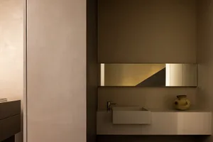 Modern minimalist bathroom with concrete walls and floor, featuring a sleek sink and mirror, creating a clean and serene spac