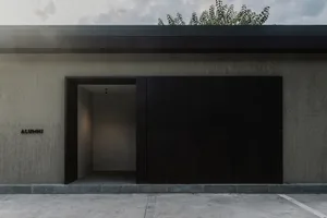 Minimalist building exterior with black metal panels and a concrete base, viewed from the parking garage.