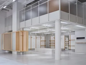 A minimalist retail store featuring white walls, concrete flooring, and wooden shelves.
