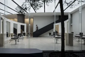 A sleek, modern salon interior with black and white color scheme, glass walls, and metal chairs.