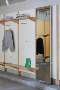 A modern clothing store interior with wooden shelving and a glass wall