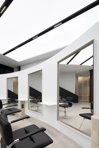 A modern minimalist hair salon with black and white color scheme and metallic black furniture.