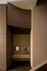 Modern, minimalist bathroom with concrete walls and floor, featuring a sleek, contemporary sink and mirror.