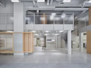A modern office environment featuring white concrete walls and floors.