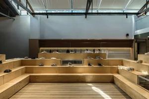 一間現代風格的零售鞋店，採用極簡設計，木質內裝搭配木製鞋架展示鞋款。