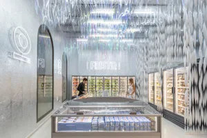 A modernista retail space with a glass ceiling and an array of products displayed in refrigerators and freezers.
