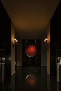 A dimly lit, dark hallway featuring a red metallic sphere display on the wall.