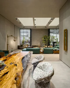 A modern industrial living room featuring a metal structure, green sofas, and a wooden coffee table.