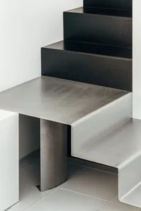 Modern, minimalist interior design featuring a sleek, metallic staircase with wooden steps.