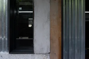 A close-up of a modern architectural window with a concrete wall and wooden and aluminum framing.