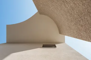 A modern building with a textured concrete exterior against a clear blue sky.