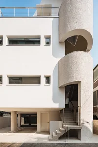 A modern building with a curved concrete exterior and a spiral staircase.
