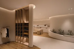 A minimalist retail store interior with wooden shelves and curved white walls.