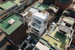 A minimalist white concrete building in an urban residential area with modern architectural features.