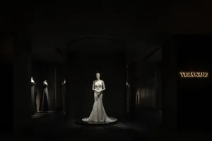 A mannequin dressed in a white wedding dress on display in a dark, elegant interior space.