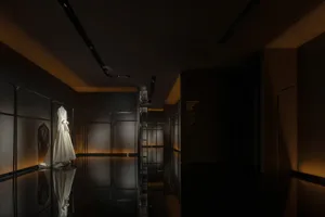 工業風格的展覽展示，展示架上掛著一件白色洋裝。