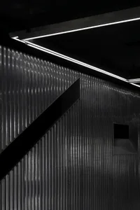 Modern industrial interior with corrugated metal walls and minimalist lighting.