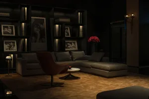 A modern industrial living room featuring dark-furniture, a couch, a coffee table, and a vase of flowers.