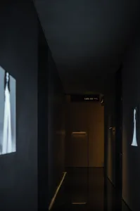 A minimalist dark corridor with white walls, white panels, and a golden glow.