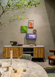 Modern dining room with wood and concrete furniture, green plants, and minimalist decor.
