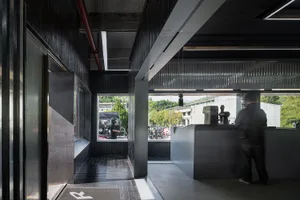 A person wearing a helmet stands at a dark wood coffee shop counter.