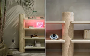 A modern limestone bookshelf with a pink heart-shaped neon light and a decorative eye-shaped object.