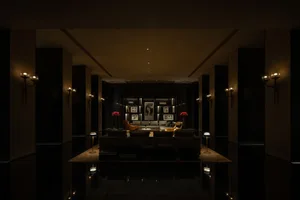 A minimalist modern lobby features a sleek and contemporary design with dark walls and floors, mixed materials, and illuminat