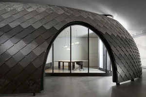 Modern office interior featuring metallic scalloped wall with arched doorway leading to a conference room with sleek design