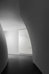 A modern minimalist interior featuring white marble accents and curved walls.