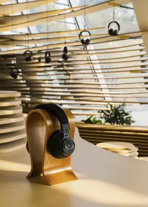 Black headphones displayed on a wooden stand in an industrial showroom with a wooden slatted ceiling.