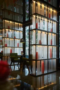 Modern restaurant interior with glass panel divider and green seating area.