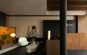 A modern lobby area featuring a wooden paneling wall with a seating area and a reception desk. The design includes minimalist