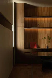 A modern office space featuring wooden paneling with built-in shelves.
