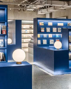 A modern bookstore interior designed with blue wooden shelves and spherical lights.