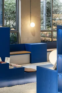 Indoor library with blue wooden panels and natural light coming through windows.